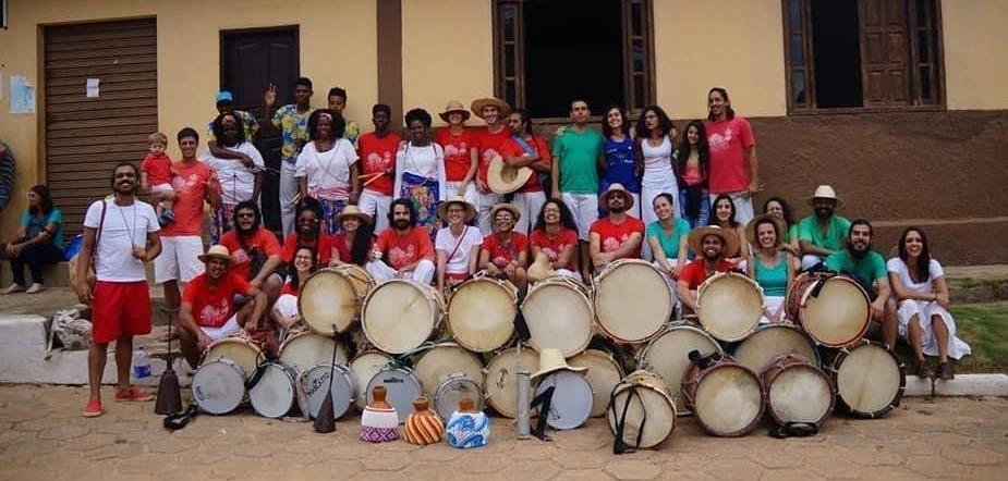 Grupos percussivos reunidos com suas alfaias em frente a uma igreja em Airões.